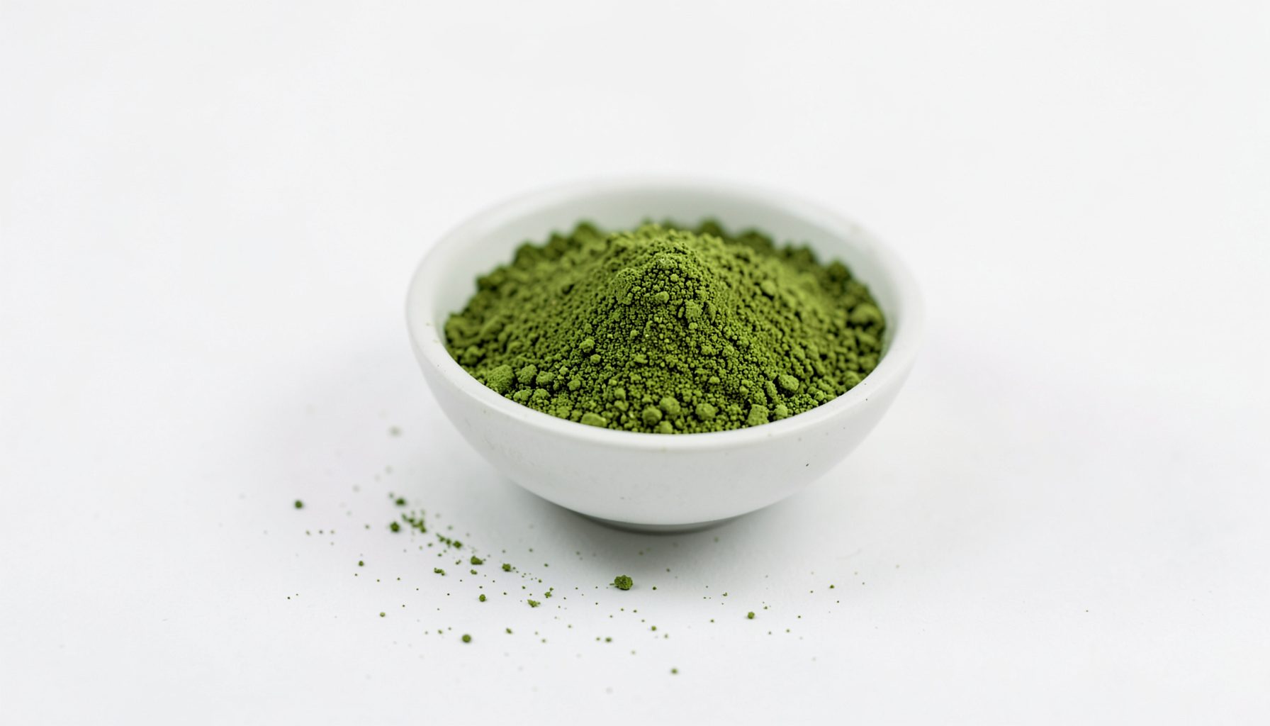 Un bol de poudre de thé vert matcha finement moulue, d'un vert vif et profond, posé sur une surface claire et épurée, évoquant fraîcheur et bien-être naturel.